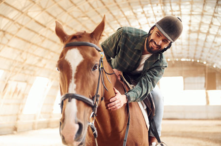 Jockey is in the saddle. Young man with a horse is in the hangar.の写真素材