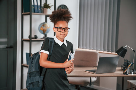 Ready for the school. Cute little girl is standing indoors in domestic room.