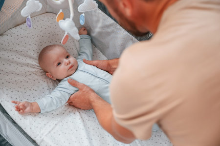 Newborn baby is in the cradle. Father is indoors. Conception of single dad.