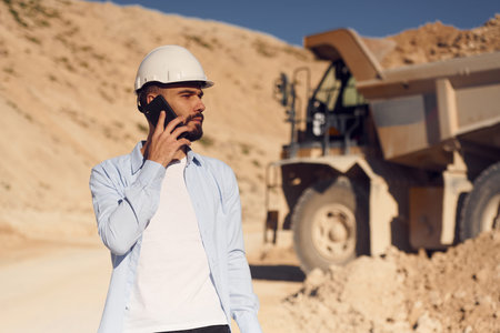 Talking by phone. Man in uniform is working in the quarry at daytime.の写真素材