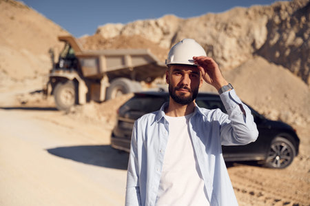 Posing for a camera. Man in uniform is working in the quarry at daytime.