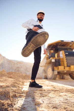 Having fun, making a kick by leg. Man in uniform is working in the quarry at daytime.
