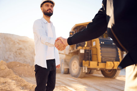 Quarry worker making a deal with colleague. Shaking hands.