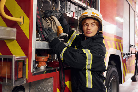 Taking equipment from the truck. Woman firefighter in uniform is at work in department.