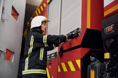 Taking equipment from the truck. Woman firefighter in uniform is at work in department.