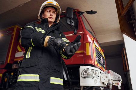 Wearing protective equipment. Woman firefighter in uniform is at work in department.