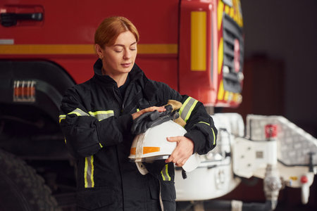 Holding helmet. Woman firefighter in uniform is at work in department.