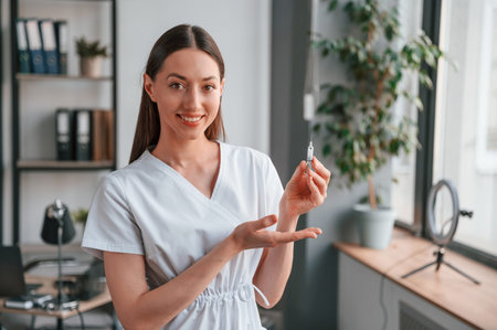 Syringe with medicine. Young beautiful female doctor in white coat is in the office.の写真素材