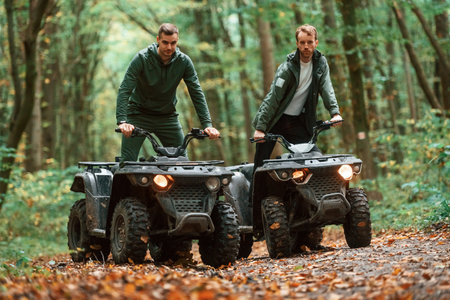 Two male atv riders is in the forest together.の写真素材