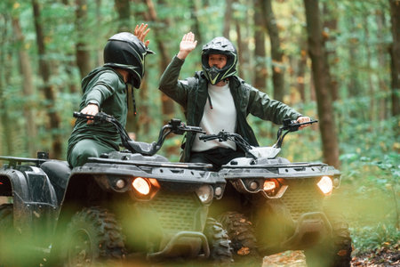 Giving high fives by the hands. Two male atv riders is in the forest together.の写真素材