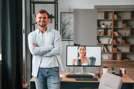 Standing against pc. Young male designer is in the modern office.