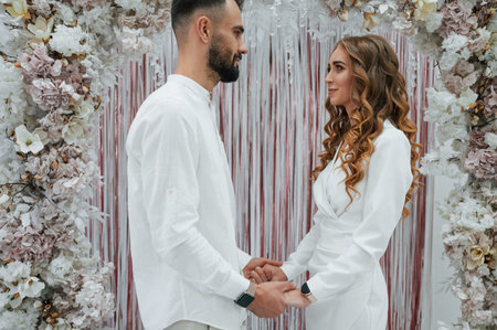 Holding by the hands. A young groom with his bride in a white dress. Wedding conception.
