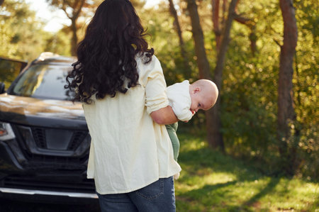 Baby is on the hands. Beautiful mother with her little son is outdoors in the forest.