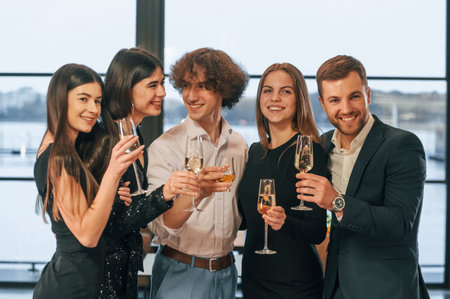 At daytime. Group of people in beautiful elegant clothes are celebrating New Year indoors together.