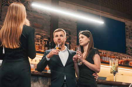 Group of people standing with glasses and celebrating event together.