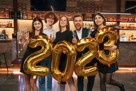 With 2023 numbers balloons. Group of people in beautiful elegant clothes are celebrating New Year...