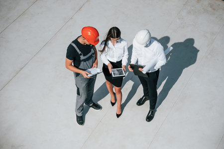 Using documents. Top view of men and woman that are on construction site, working together on the...