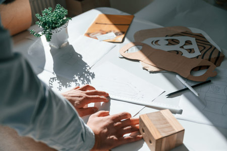 Doing measurements and drawing new design. Print house worker in white clothes is indoors.