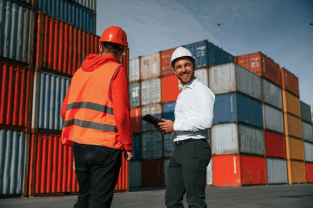 Two male workers is on the location with containers.