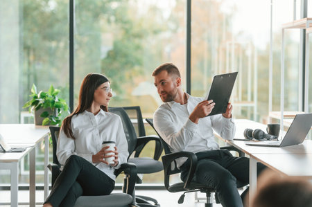 Friendly talking. Man and woman are working in the modern office together.