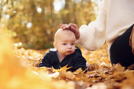 Mother with her little baby son is sitting in the forest.