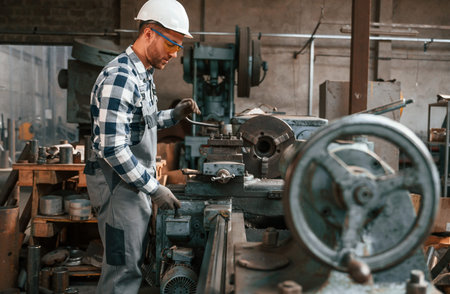 Factory male worker in uniform is indoors.