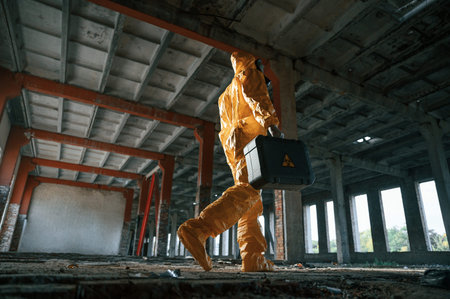 View from below. Man dressed in chemical protection suit in the ruins of the post apocalyptic...