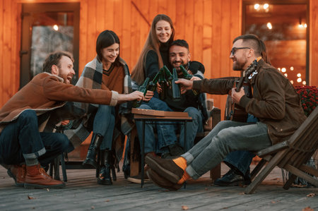 Positive emotions. Group of people is together near beautiful wooden building at evening time.の写真素材