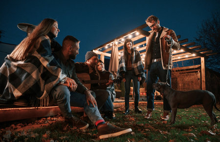 Evening time. Group of people is spending time together on the backyard.の写真素材