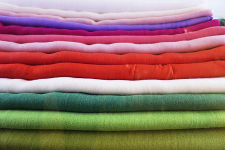group of colored sweaters on top of each other on displayの写真素材