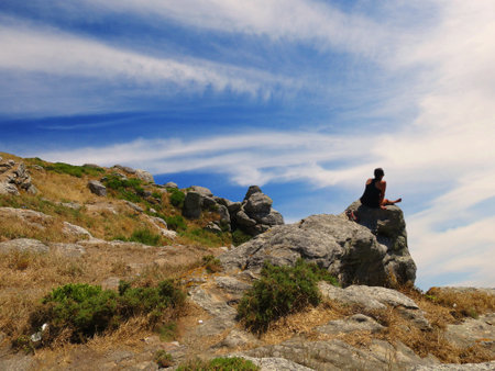 girl sitting on a rock looks at the horizonの写真素材
