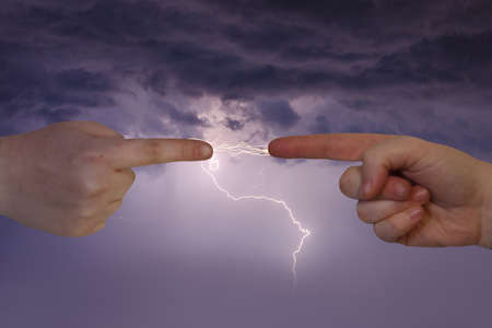 two human fingers point and exchange lightning boltsの写真素材