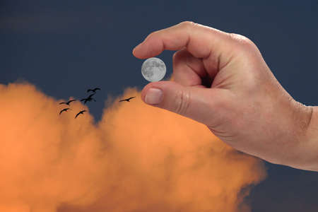 sunset moon between the fingers of the handの写真素材