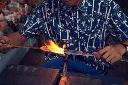 Workers are using the heat of gas blowing glass to look as art, shape, light, flame beautiful.