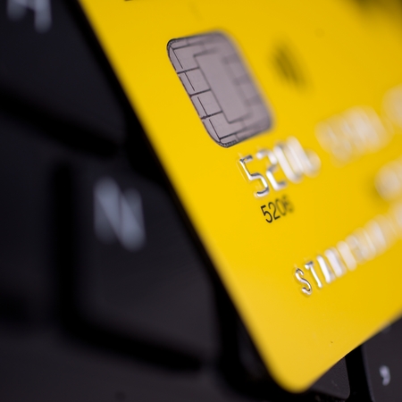 yellow credit card on black keyboard backgroundの写真素材