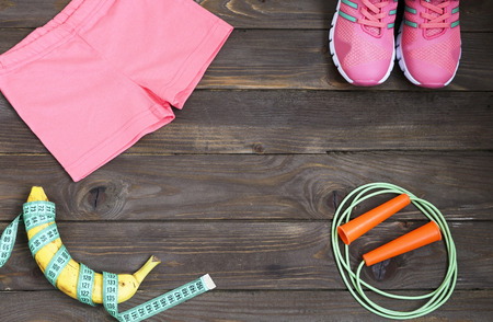 Sports apparel, skipping rope, banana and measuring tape on wooden background .Sport, diet and healthy lifestyle concept. Clothing, equipment and fitness accessories. The place to advertise.の写真素材