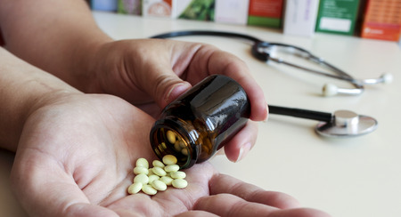 A young woman pours the pills out of the bottleの写真素材