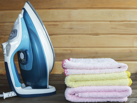 Iron, electric tool. Ironing colorful towels on wooden tableの写真素材