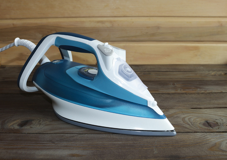 Iron on a wooden table. Ironing steam cleaning electric tool.の写真素材