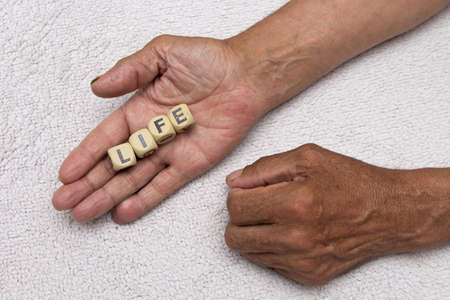 The elderly man is holding the dice with the inscription life. The concept of retirement.の写真素材