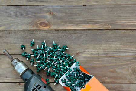 Roofing screws and a drill on a wooden table. The view from the top. Template for labor day .Roofer,...