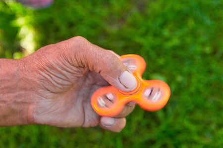 Orange Spinner in the hands of an elderly man, on nature background with copy spaceの写真素材