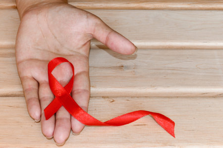 The symbolic conception of the world day of fight against AIDS. The red ribbon in the hands of a ...