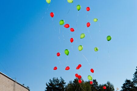 Balloons. The children released a lot of balls with ropes in the sky.Red  and green balloons in the blue sky in the rays of the sun. Selective focus.の写真素材