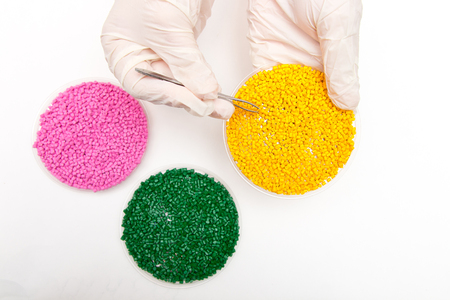 Plastic pellets . Colorant for polymers in granules. Plastic pellets in the hands with gloves and tweezers の写真素材