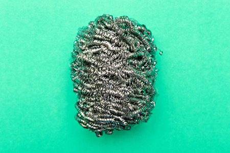 Metal sponge for washing dishes closeup on a colored background with copy spaceの写真素材