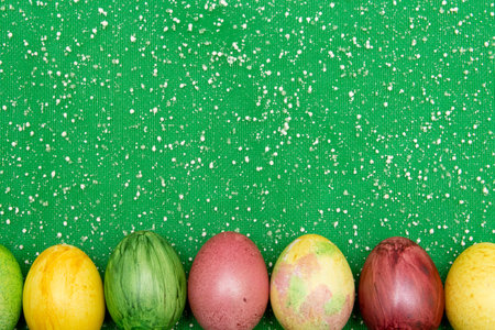 Colorful easter eggs on green organza fabric background. Eggs handmade new style of colouring ....