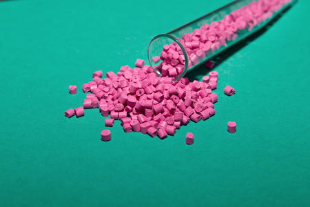 Plastic pallets . Plastic raw materials in granules for industry. Polymeric dye pink on a turquoise background. Plastic granules after processing of waste polyethylene and polypropylene.Polymer.の写真素材