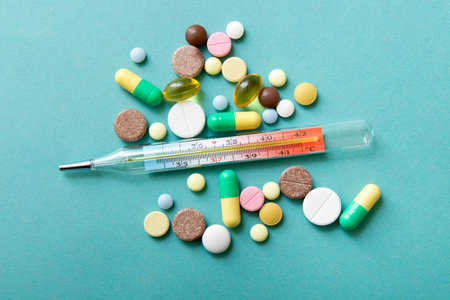  A thermometer with a color pills on turquoise background with copy space.The mercury thermometer to...