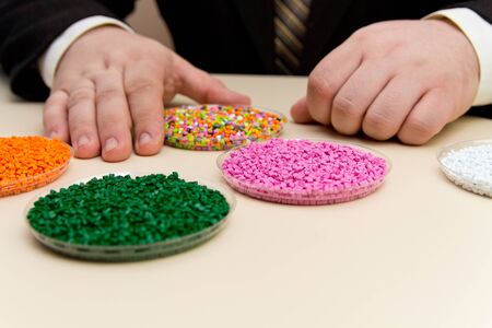 Businessman inspects plastic pellets for industry. Plastic raw materials in granules . Polymer, plastic resin. The dye in the granules of polypropylene and polyethylene.の写真素材